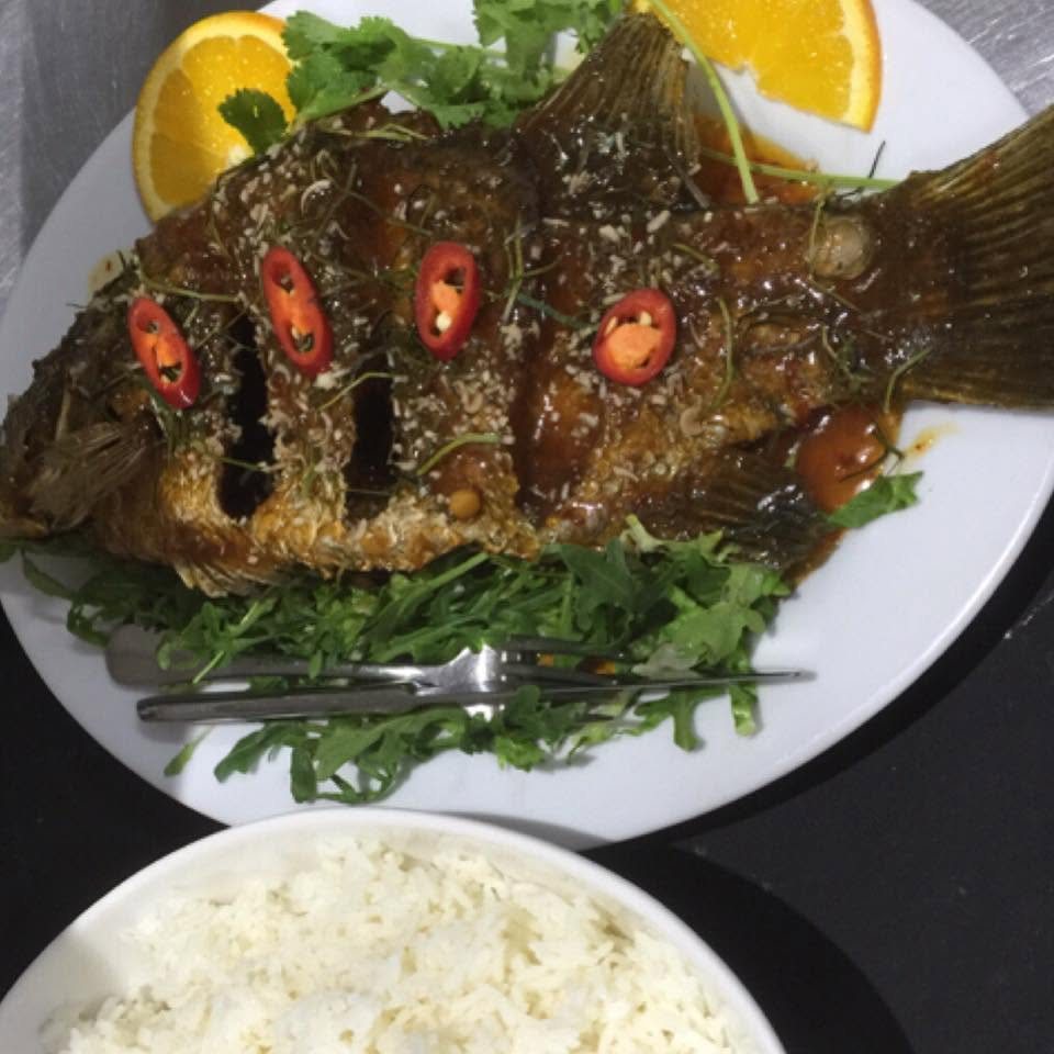 A crispy whole fish with chilli, salad, orange and rice
